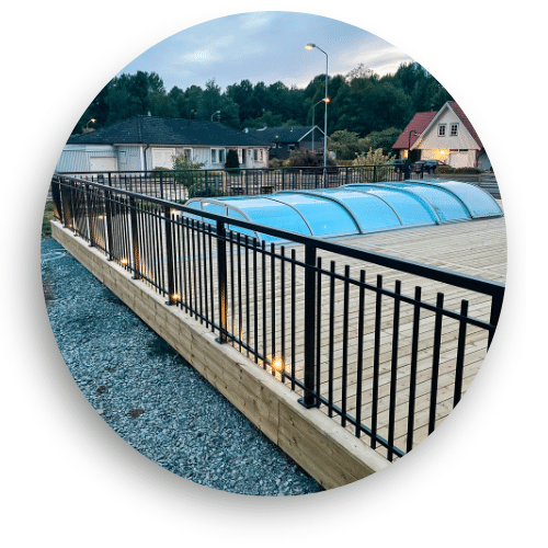 Mustaksi pulverimaalattu takorautakaide alumiinista, puuterassin ja allassuojan rajana – yhdistää klassisen ulkoasun ja turvallisuuden.