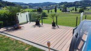 Terassi, jossa yhdistyy huurrelasi ja kirkas lasiaita uima-altaan ympärillä, maisemaa kehystävät palmut ja avoin luonto.