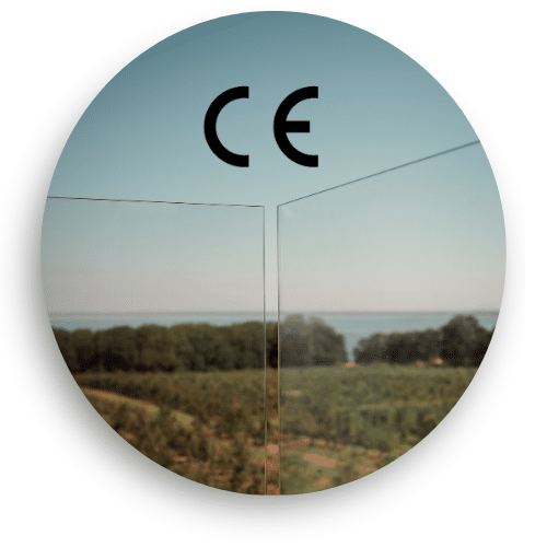 Lähikuva CE-merkitystä laminoidusta lasista, käytössä lasiaidassa – avara näkymä skånelaiselle maaseudulle.