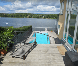 Vaijerikaide ruostumattomasta teräksestä puuterassin ja altaan ympärillä, näkymä järvelle – huomaamaton ja turvallinen ratkaisu korkeuseroihin.