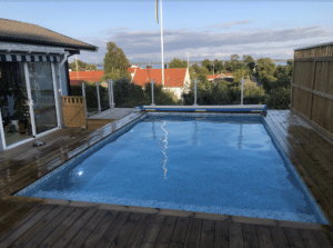 Valkoisesta alumiinista valmistettu lasiaita asennettuna korotetun puutarha-altaan ympärille – turvallinen ja tyylikäs ratkaisu merinäköalalla.