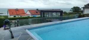 Moderni lasiaita uima-allasalueen ympärillä, merinäköalalla – tyylikäs ratkaisu, joka suojaa peittämättä ympäristöä.